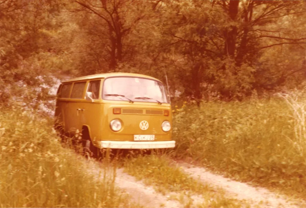 Ein VW-Bus auf einem Feldweg am Waldrand