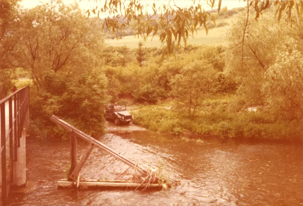 Ein Geländewagen am Flussufer neben einem Steg