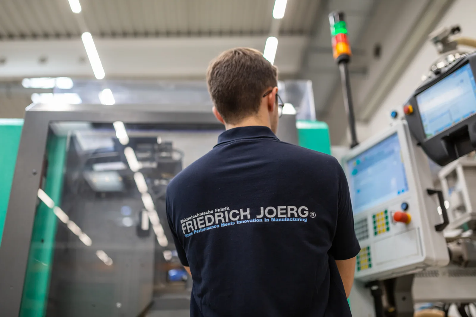 FJ-Mitarbeiter überwacht eine Spritzgussmaschine an der Steuerung