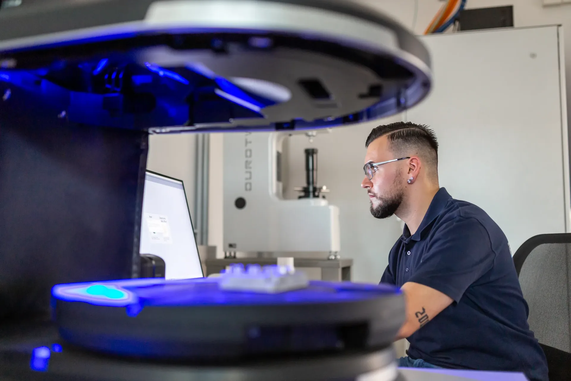 Mitarbeiter prüft ein Bauteil an einer optischen Koordinatenmessmaschine
